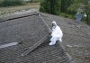 Un operaio che lavora allo smaltimento dell'amianto su un tetto