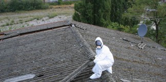 Un operaio che lavora allo smaltimento dell'amianto su un tetto